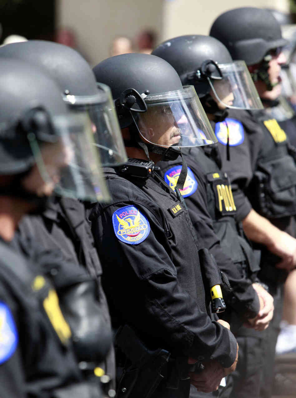 Phoenix police form a cordon to block the street while protesters rally against Arizona's new immigr Phoenix police form a cordon to block the street while protesters rally against Arizona's new immigr